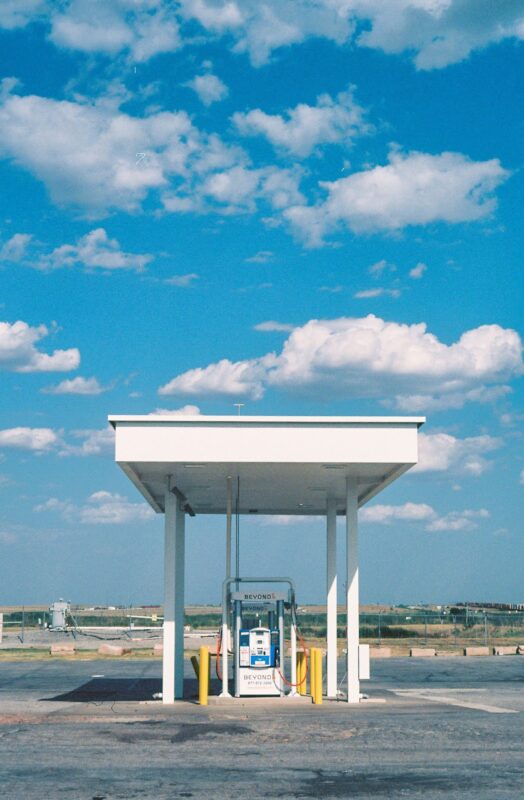 A solitary gas station in a vast open landscape under beautiful blue skies with scattered clouds.