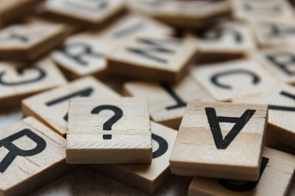 Close-up of wooden Scrabble tiles with letters and symbols, focusing on creativity and language.